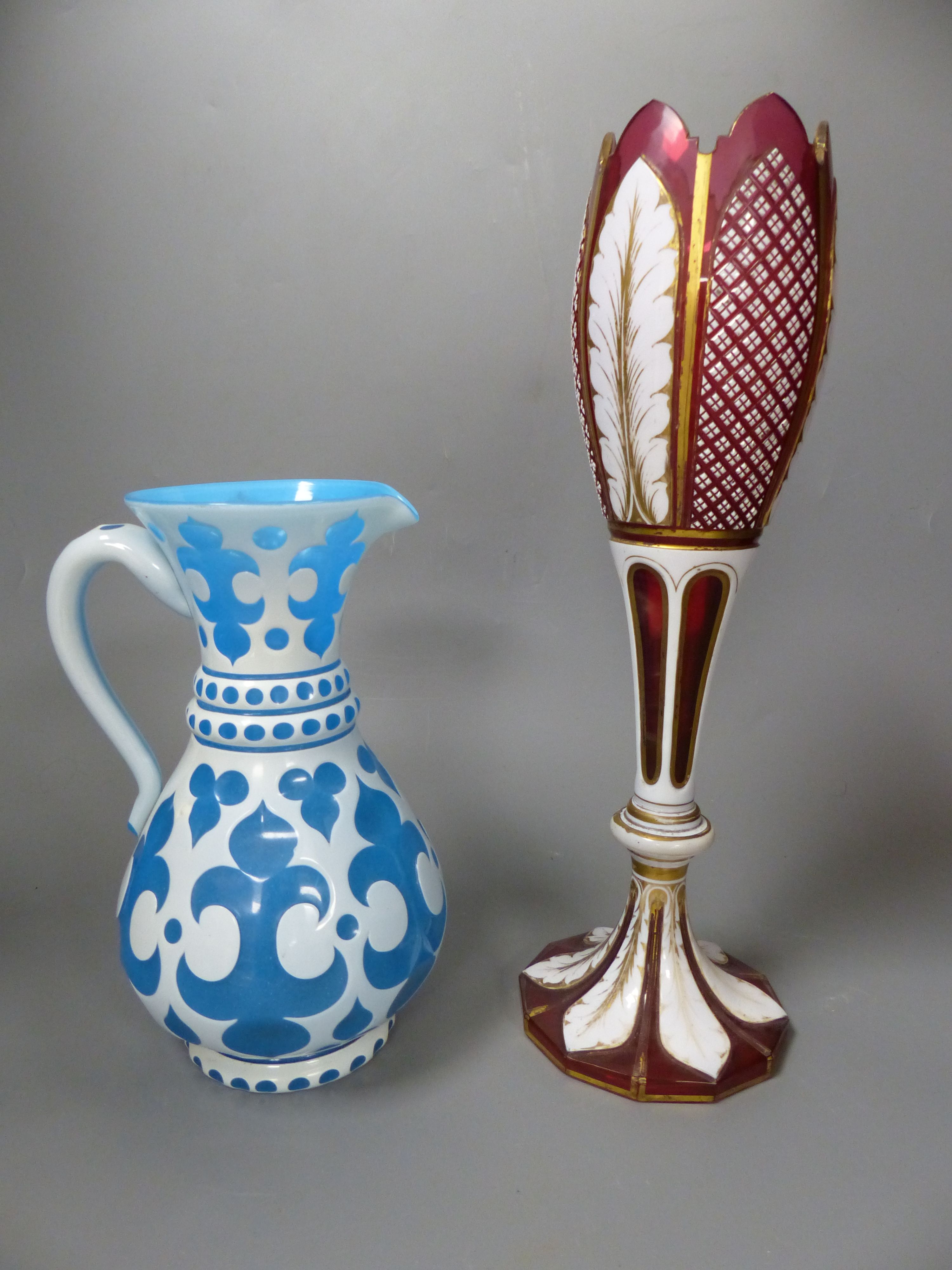 A Bohemian blue and white overlaid glass jug and a similar ruby and white overlaid glass vase, tallest 35cm